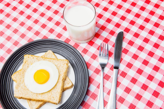 Un bicchiere di latte con uova fritte e pane tostato integrale