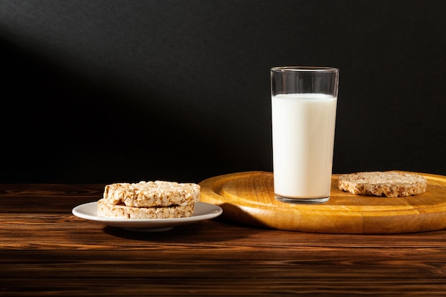 Un bicchiere di latte e biscotti sulla tavola di legno sul nero