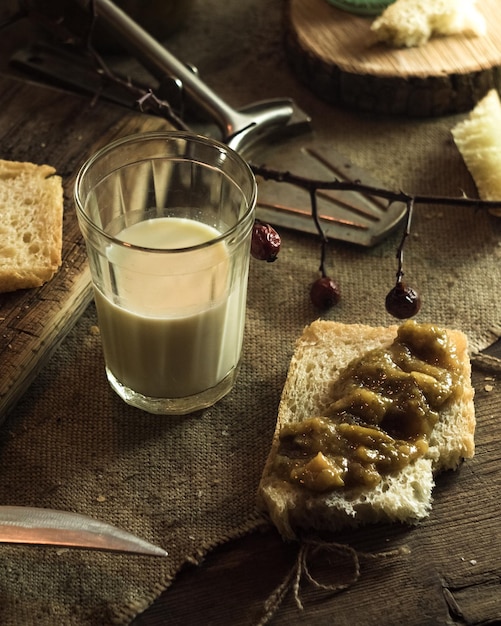 Un bicchiere di latte e un pezzo di pane con marmellata, foto sobria, latte