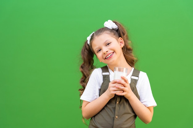 Un bicchiere di latte sano nelle mani di una bambina un bambino con latte su uno sfondo isolato