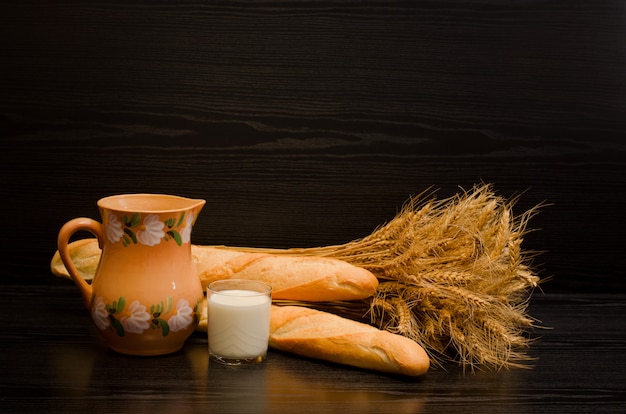 Un bicchiere di latte, una brocca e un covone di pagnotte