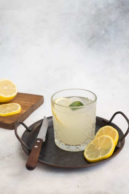 Un bicchiere di limonata con limone su sfondo grigio