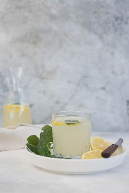 Un bicchiere di limonata con limone su sfondo grigio