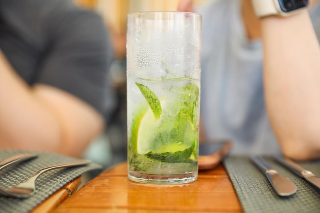 Un bicchiere di mojito su un tavolo con un uomo seduto al tavolo.