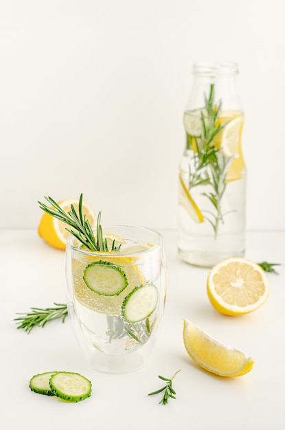 Un bicchiere di rinfrescante limonata estiva o acqua disintossicante con limone e rosmarino sul tavolo bianco. Concetto di assistenza sanitaria. Copia spazio