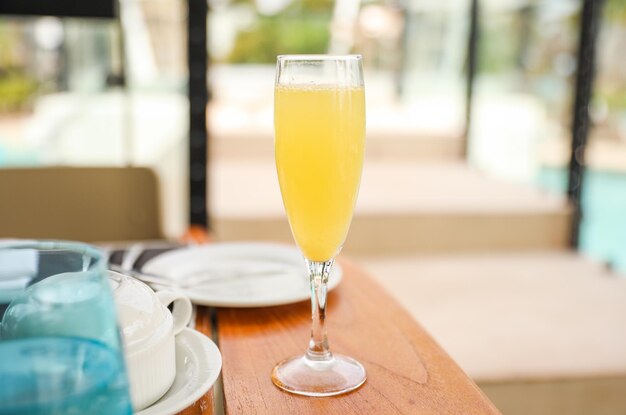Un bicchiere di succo d'arancia si trova su un tavolo con una tovaglia blu e un bicchiere di succo d'arancia.