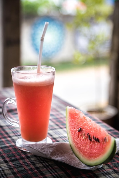 Un bicchiere di succo di anguria e una cannuccia su un tavolo.