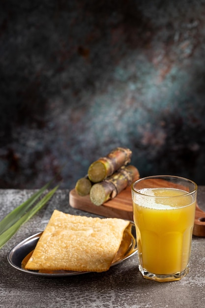 Un bicchiere di succo di canna da zucchero con pasticceria fritta Uno spuntino tipico brasiliano