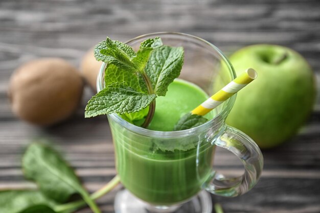 Un bicchiere di succo verde sano in primo piano sul tavolo