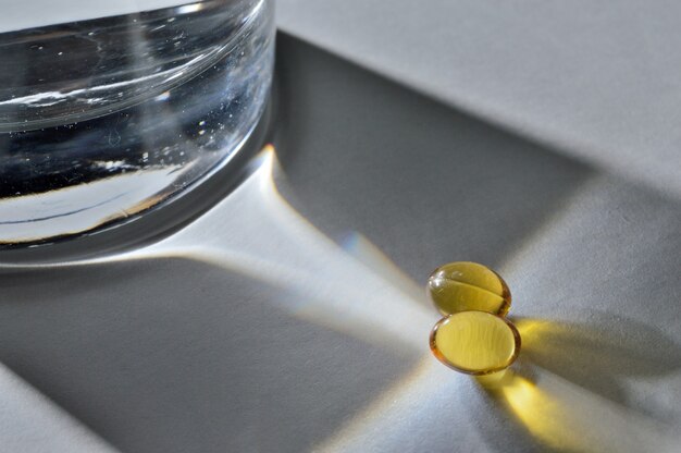 Un bicchiere di vetro e due compresse gialle con vitamine. avvicinamento.