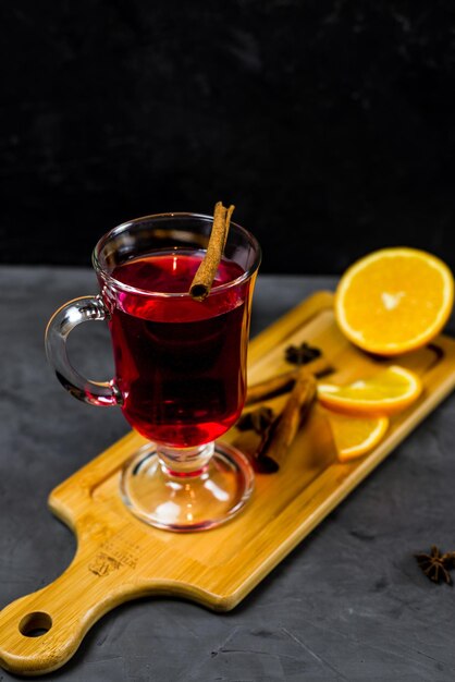 Un bicchiere di vin brulè con sopra una stecca di cannella.