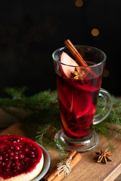 Un bicchiere di vin brulè con spezie e una torta di frutti di bosco