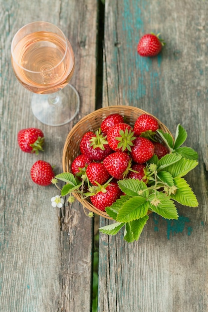 Un bicchiere di vino rosato servito con fragole fresche su una superficie di legno