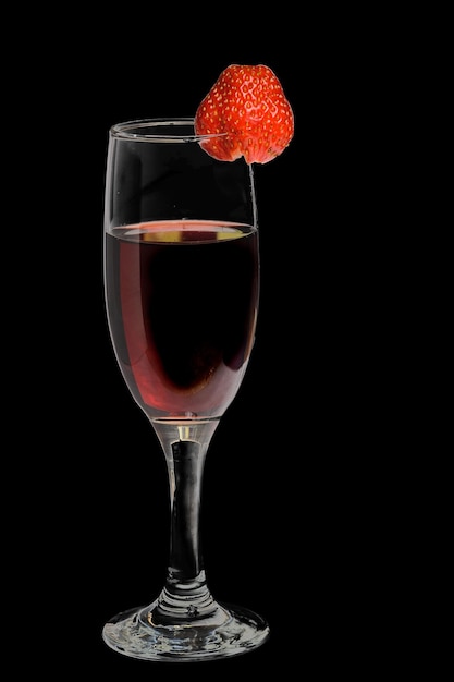 Un bicchiere di vino rosso con fragole su sfondo nero