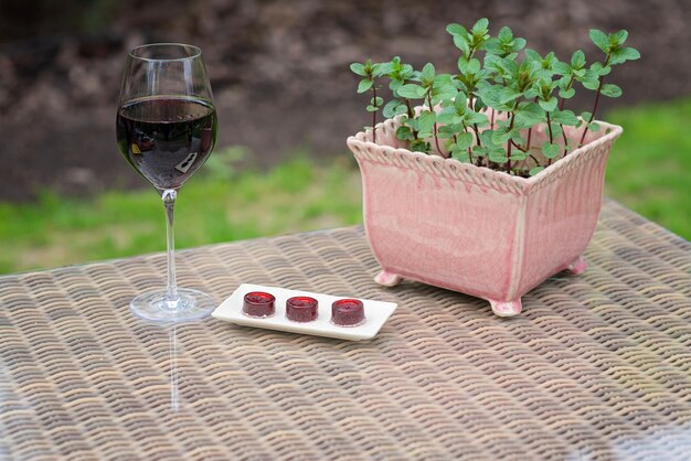 Un bicchiere di vino rosso e marmellate di caramelle su un tavolo accanto a una pentola di menta.