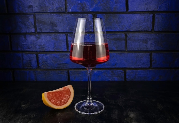Un bicchiere di vino rosso e una fetta di pompelmo