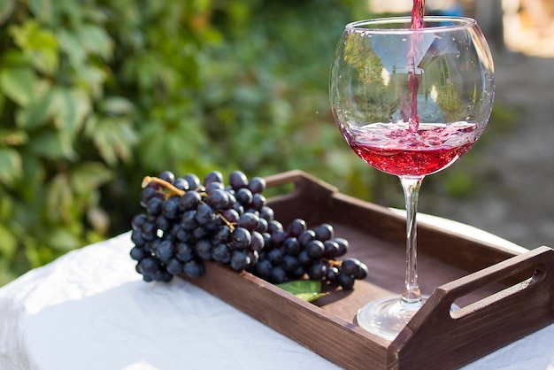 Un bicchiere di vino rosso preparato per la degustazione si trova su un tavolo con una tovaglia bianca all'aperto alla luce del sole