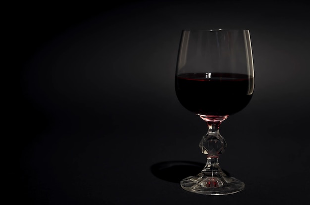 Un bicchiere di vino rosso Vino rosso in un bicchiere trasparente con riflessi Sfondo nero Concentrarsi sul vetro