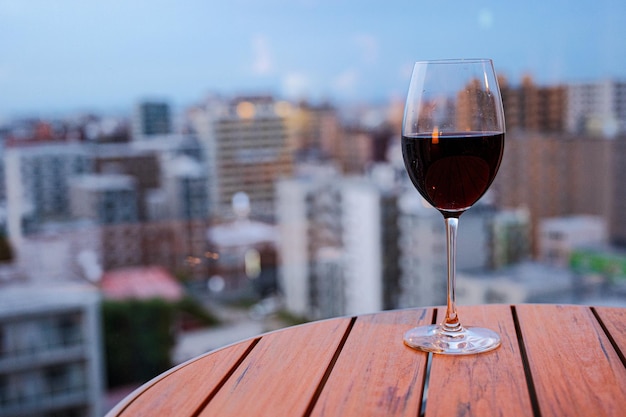 Un bicchiere di vino si trova su un tavolo davanti a un paesaggio urbano.