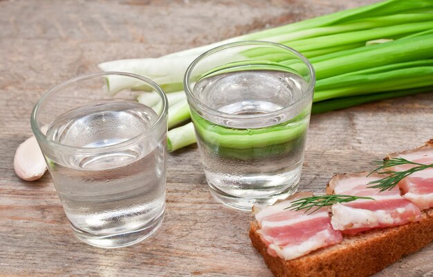 Un bicchiere di vodka, cipolle e panino al bacon.