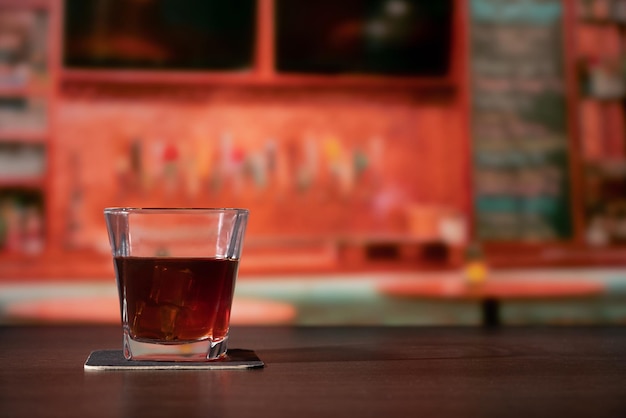 Un bicchiere di whiskey sul bar davanti alla barra dell'immagine sfocata