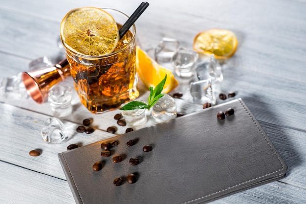 Un bicchiere di whisky con ghiaccio su fondo di legno bianco