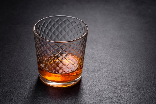 Un bicchiere di whisky o cognac su un tavolo di cemento nero Tempo di relax