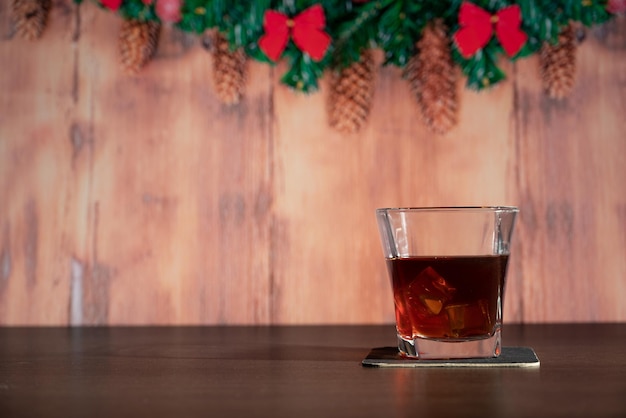 Un bicchiere di whisky sul bar di fronte all'immagine sfocata camera di casa di Natale con albero e illuminazione bokeh festiva sfocata sullo sfondo delle vacanze