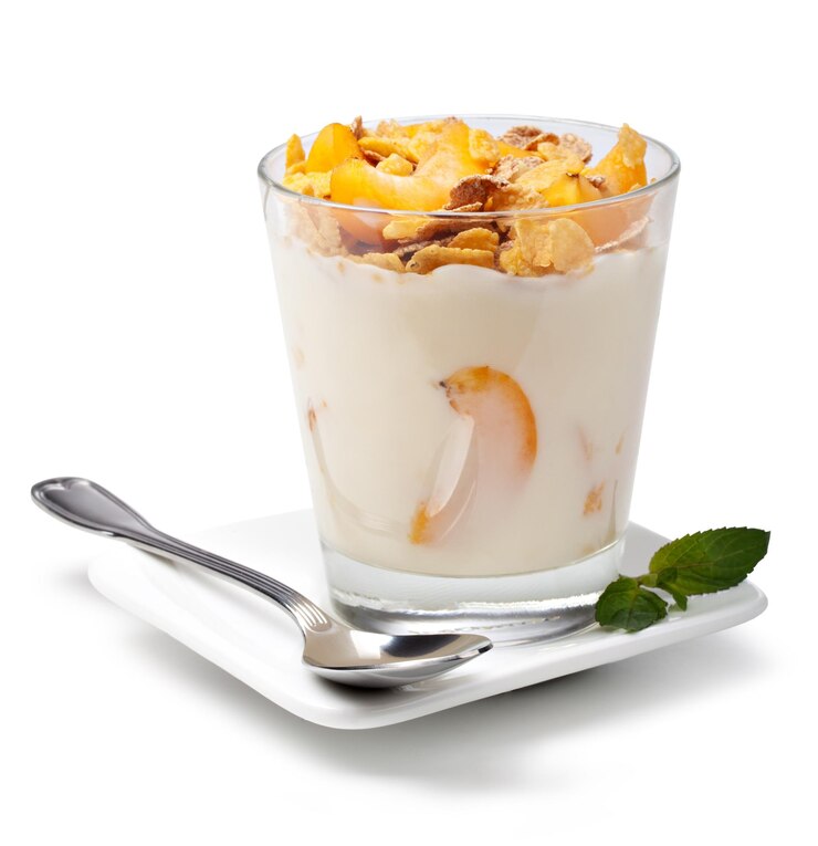 un bicchiere di yogurt con un cucchiaio e un cucchio su un piatto