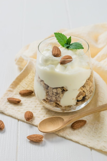 Un bicchiere di yogurt muesli e frutti di bosco su un panno su un tavolo bianco