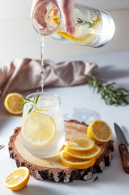 Un bicchiere e una caraffa di limonata Fette di limone con foglie di rosmarino in una bevanda