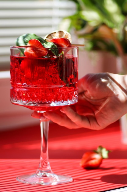 Un bicchiere trasparente di cocktail alla fragola con fragole in cima Mojito alla fragola cocktail rosso