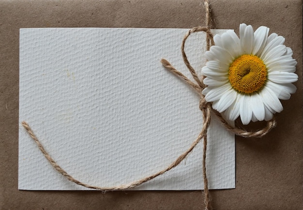 Un biglietto di auguri vuoto con una busta marrone e un fiore bianco per la mamma su un tavolo di legno in stile vintage e con vignette