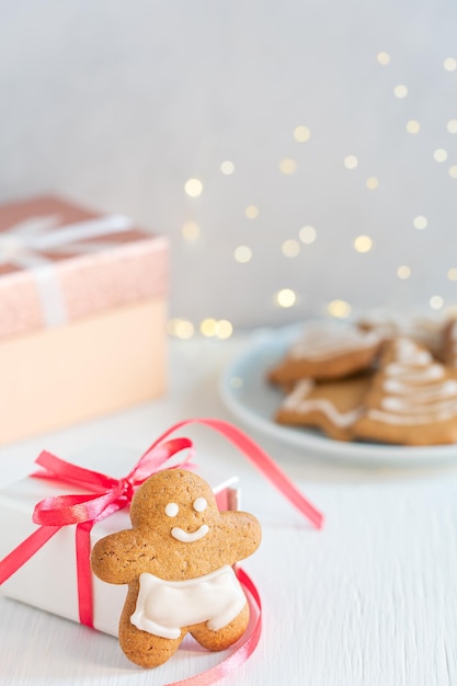 Un biscotto di pan di zenzero fatto in casa in piedi sul tavolo bianco con confezione regalo preparata per la celebrazione