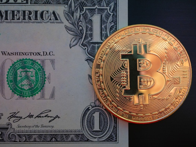 Un bitcoin d'oro giaceva su una banconota da un dollaro