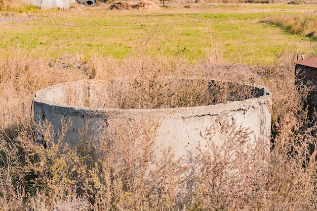 Un blocco di fossa circolare in cemento abbandonato giace sul terreno intorno agli impianti a secco Sito ad anello di produzione Magazzino robusto Fabbrica industriale Produzione di materiale Tubo tondo Sezione circolare