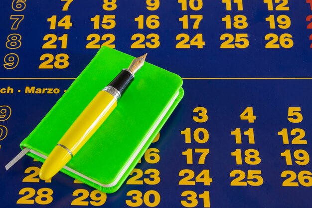 Un blocco note verde su un calendario di carta blu con numeri di carta colorati