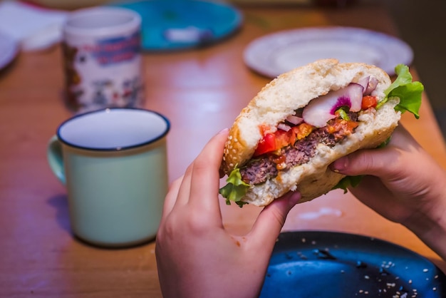 Un boccone di hamburger fatto in casa nelle mani di un bambino L'interno di mezzo hamburger