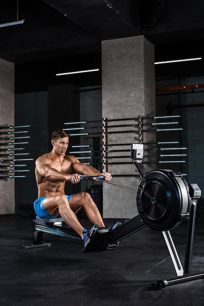 Un bodybuilder che lavora sulle gambe con una macchina per i pesi in palestra. Un giovane muscoloso in pantaloncini blu che fa esercizi.