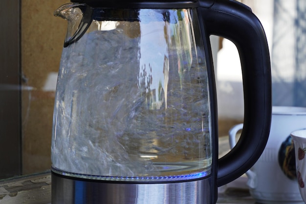 Un bollitore di vetro con acqua bollente su un tavolo