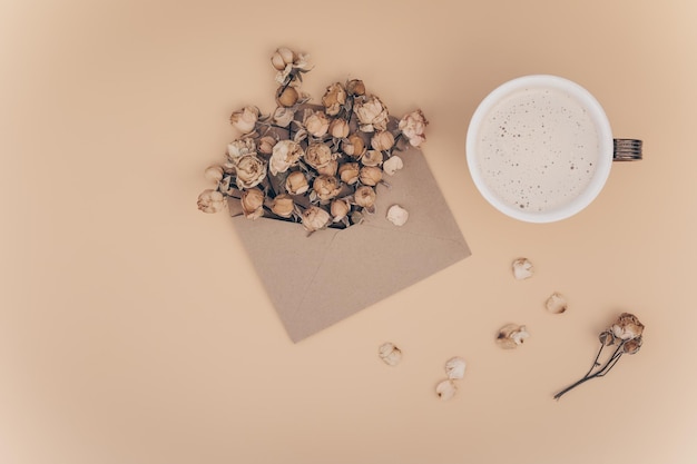 Un bouquet di fiori secchi in una busta marrone artigianale con cuo aromatico di caffè su sfondo pastello con spazio per le copie. Biglietto di auguri romantico. San Valentino solitario. Amore a distanza. Rose secche.