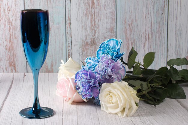 Un bouquet di garofani blu e un bicchiere di champagne Concetto di festa e vacanza