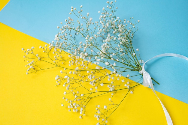 Un bouquet di gypsophila si trova su un tavolo dai colori vivaci in blu e giallo