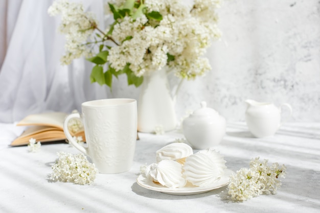 Un bouquet di lillà bianco, una tazza di caffè e un vecchio libro