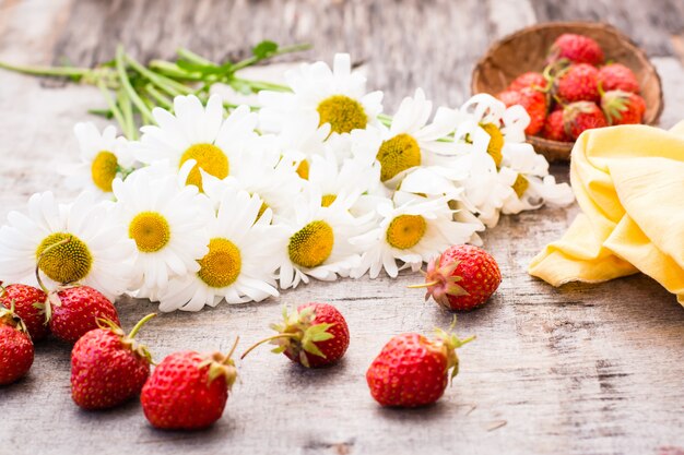 Un bouquet di margherite e fragole su un tavolo di legno