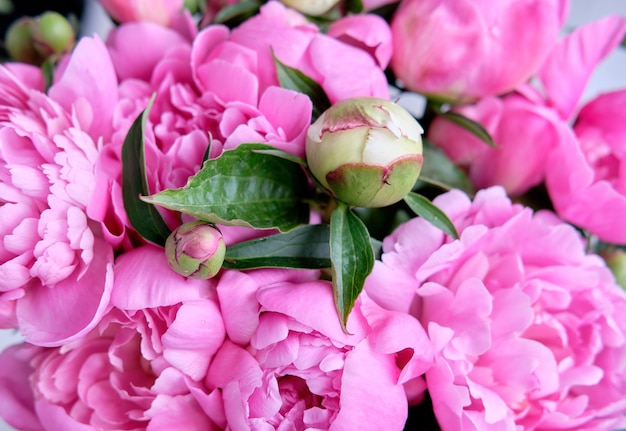 Un bouquet di peonie rosa cremisi si trovano vicino a un tavolo di legno