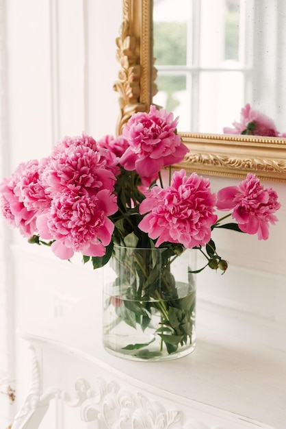 Un bouquet di peonie rosa fresche in un vaso trasparente in un interno lussuoso