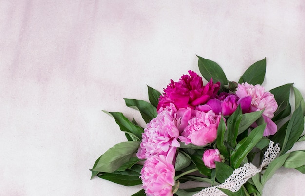 un bouquet di peonie rosa legate con un nastro di pizzo rosa