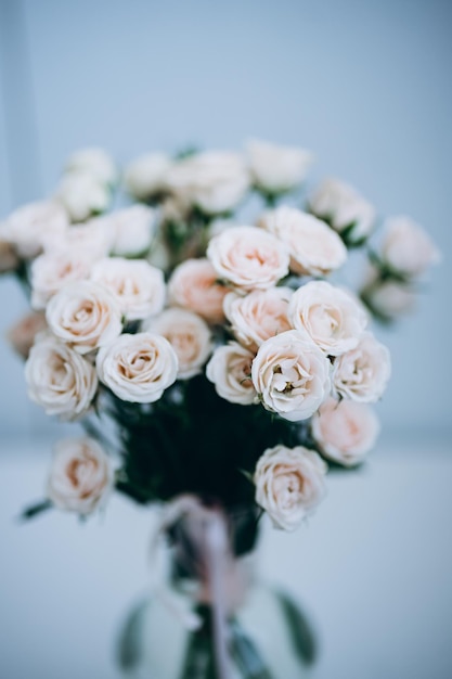 un bouquet di rose color crema in un vaso di vetro su sfondo bianco