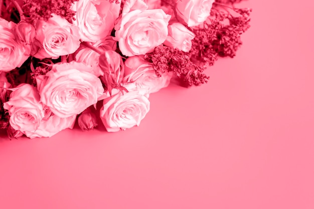 Un bouquet di rose pallide e fiori viola brillante in piena fioritura su uno sfondo rosa con spazio per il biglietto di auguri di testo tonica in viva magenta colore di tendenza dell'anno 2023